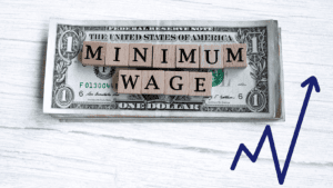 Minimum wage spelt out in alphabet blocks on a stack of dollar bills.